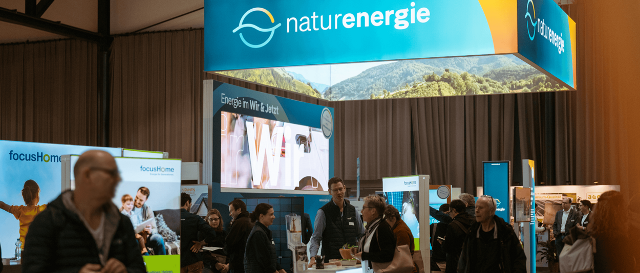naturenergie-Messestand mit großem Banner und mehreren Infostationen in einer Messehalle